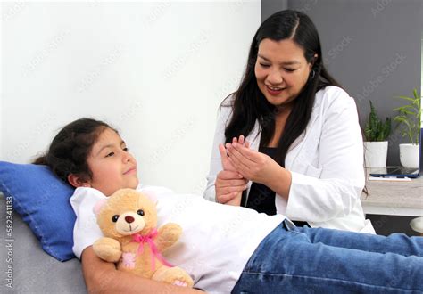 Latina Female Pediatrician Doctor Attends To Her Year Old Girl Patient Checks Her Fingers