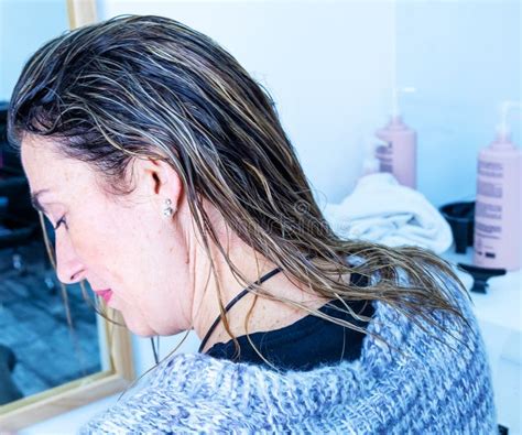Lady Combs Her Long Blonde Hair Before Starting To Dry It Stock Photo