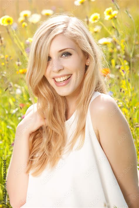 Hübsche blonde Frau vergnügt sich auf einer Blumenwiese Stock Photo