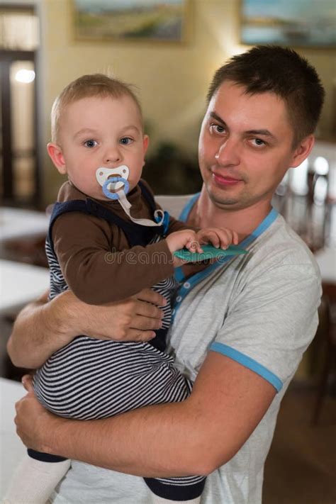 Bébé S asseyant Sur Les Bras De Son Père Image stock Image du soin