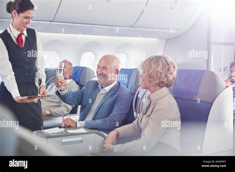 Flight Attendant Serving Champagne To Mature Couple In First Class On Airplane Stock Photo Alamy