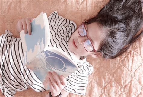 A girl lying down reading a book on a weekend Stock Photo | Adobe Stock