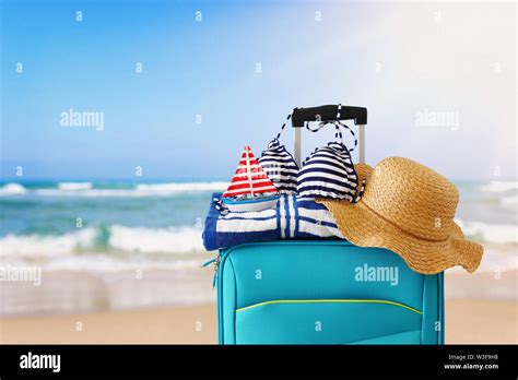 Holidays Travel Concept Blue Suitcase With Female Hat Bikini Sailing Boat And Beach Towel In