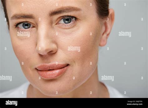 Portrait Of Beautiful Woman With Blonde Hair Posing On Gray Background And Looking At Camera