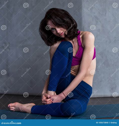 Pretty Brunette Model In Sportswear Posing Sitting On Floor Barefoot In Studio Looking At Camera