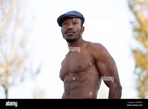 Low Angle Of Determined African American Male With Naked Muscular Torso Standing In Nature And