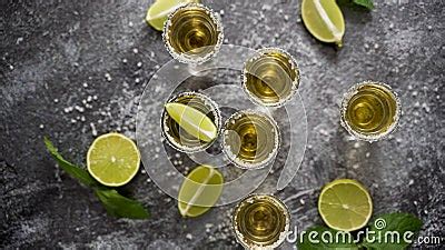 Top View Of Golden Tequila Shots Served With Lime And Sea Salt On Table