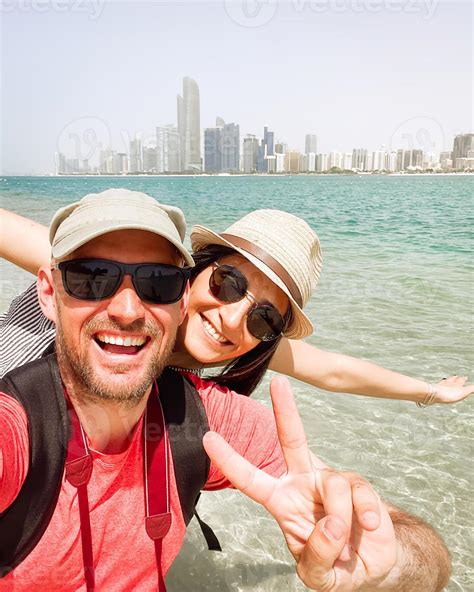 Couple of tourists having fun wave take selfie in Abu dhabi city beach