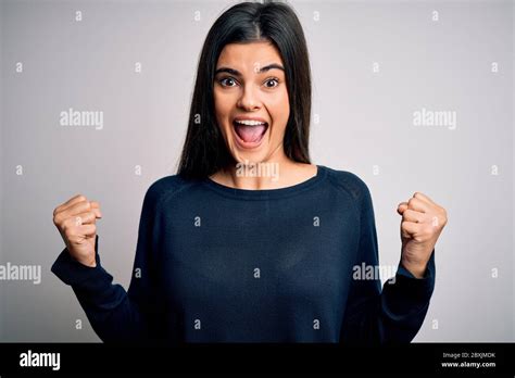 Jeune femme de la belle brunette portant un pull décontracté debout sur fond blanc célébrant