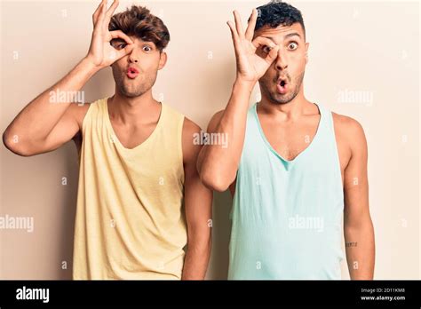 Jeune gay couple portant des vêtements décontractés faisant geste ok choqué avec le visage