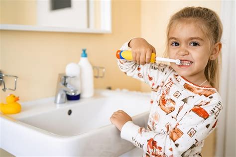 Une Jolie Petite Fille Blonde Se Brosse Les Dents Avec Une Brosse