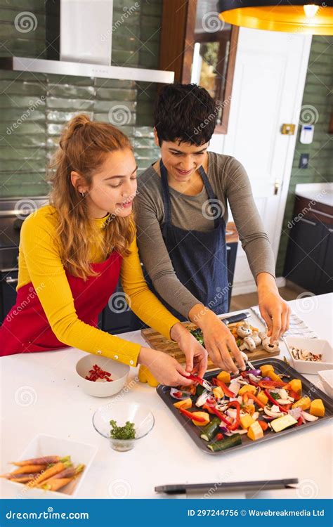 Happy Biracial Lesbian Couple Cooking Seasoning Chopped Vegetables In Kitchen Copy Space Stock
