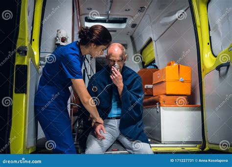 Man Sits In Blanket With Oxygen Mask Doctor Holds His Hand In The