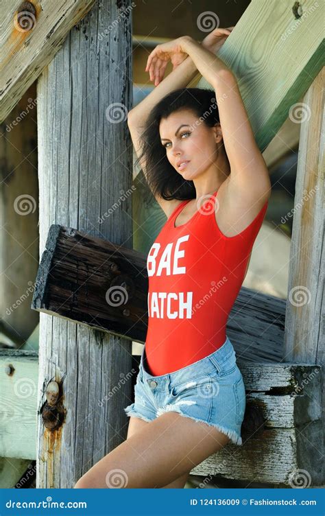 Attractive Brunette Model Posing In Fashionable Red Swimsuit And Shorts