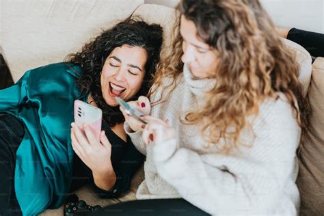 Two Women Laughing While Looking At Their Cell Phones Photo Social