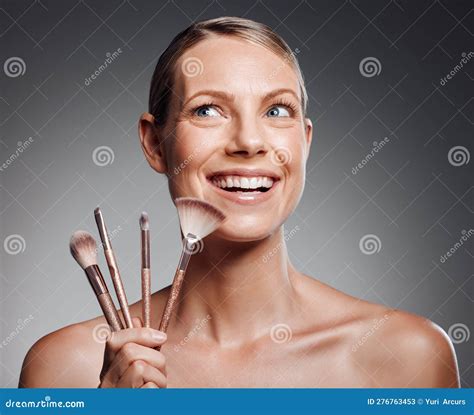 Beautiful Mature Woman Posing With Makeup Brush In Studio Against A Grey Background Stock Image