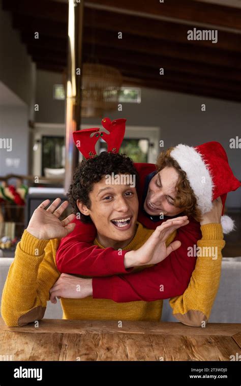 Portrait Of Happy Diverse Gay Male Couple Wearing Christmas Hats And Having Video Call At Home