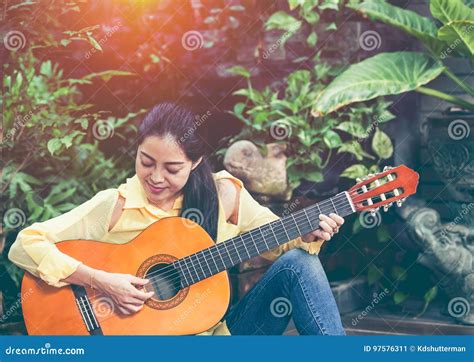 Asian Woman Playing Acoustic Guitar With Bright Sunlight Vinta Stock