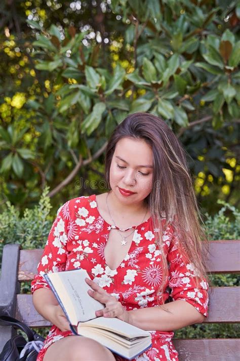 Toma Vertical De Una Mujer Latina Leyendo Un Libro En Un Parque Sentado En Un Banco Foto De