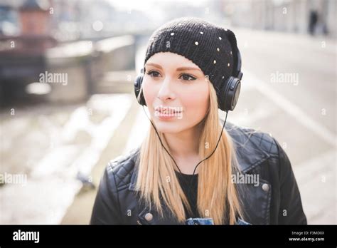 Portrait von junge schöne blonde glatte Haare Frau in der Stadt mit Kopfhörern Musik hören mit