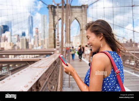 New York Tourist Woman Using Phone App Walking On Brooklyn Bridge