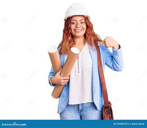 Jovem Latina Usando Um Arquiteto Hardhat Segurando Plantas Apontando Dedo Para Um Autosorridente