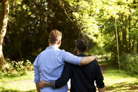 Affectionate Male Gay Couple Hugging Walking In Sunny Park Gay Men Nature Stock Photo