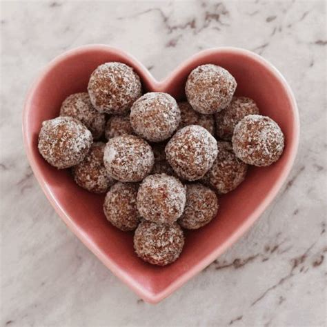 A Pink Heart Shaped Bowl Filled With Chocolate Covered Doughnuts On Top