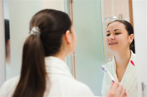 Premium Photo Pretty Female Brushing Her Teeth In Front Of Mirror