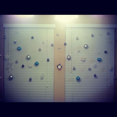 Ornaments hanging from the curtain rod in front of window for Christmas