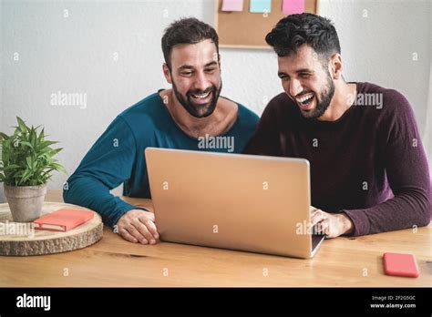 Gay Couple Having Video Call At Home Using Laptop Computer During Lockdown Isolation Focus On