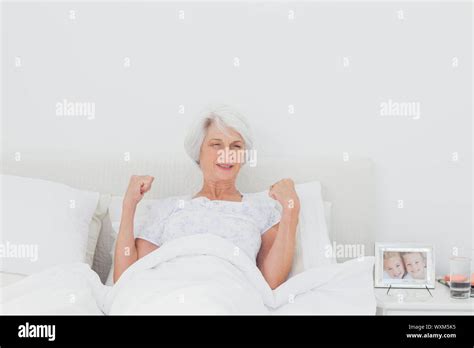 Mature Woman Stretching And Raising Arms In Bed Stock Photo Alamy