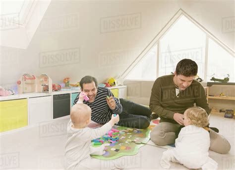 Male Gay Parents Playing With Baby Sons In Playroom Royalty Free Stock Photo Dissolve