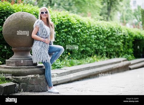 Stilvolle blonde Frau Verschleiß an Jeans Sonnenbrillen und Mädchen ärmellos mit weißem Hemd