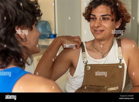A Gay Couple Shares A Warm Intimate Moment In Their Kitchen Engaging In Light Conversation And