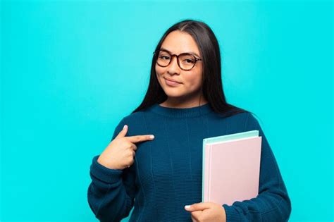Mujer latina joven que parece orgullosa segura y feliz sonriendo y apuntando a sí misma o