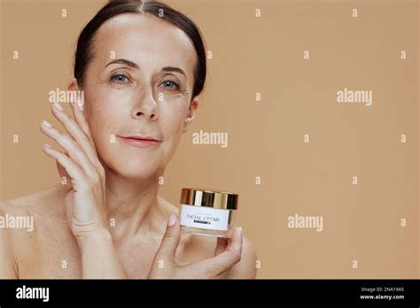 Modern 40 Years Old Woman With Facial Cream Jar Isolated On Beige Stock