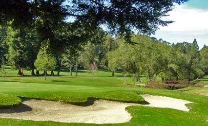 a green golf course with sand bunkers and trees in the background on a ...