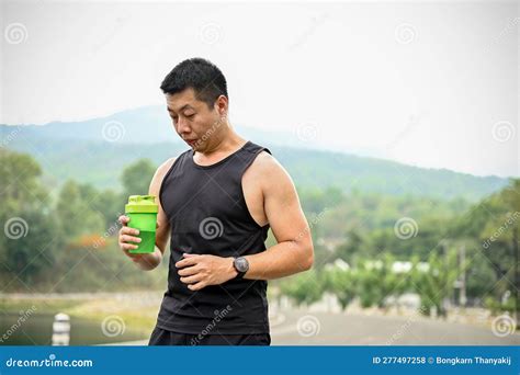 Sweaty And Thirsty Mature Asian Man In Sportswear Drinks Water From A Bottle Stock Photo Image