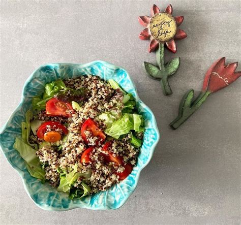 A Blue Bowl Filled With Salad Next To A Flower And Broccoli Stem Decoration