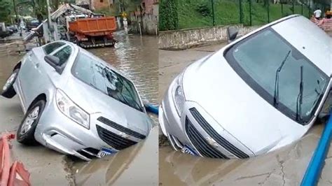 Carro cai em buraco e fica submerso em rua alagada após chuva veja vídeo