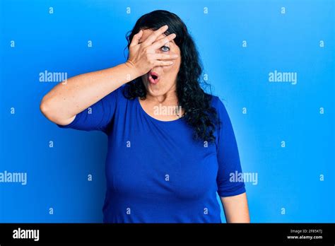 Plus Size Brunette Woman Wearing Casual Blue Shirt Peeking In Shock Covering Face And Eyes With