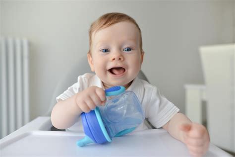 El bebé feliz está bebiendo agua de una botella Foto Premium