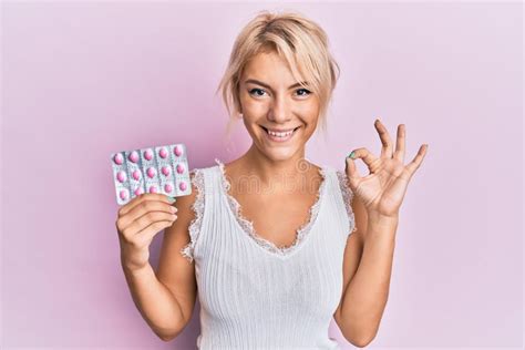 Jeune Fille Blonde Tenant Des Pilules Faisant Ok Signe Avec Des Doigts Souriant Sympathique