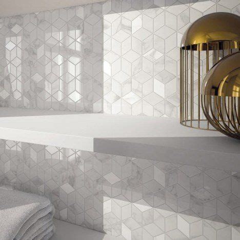 A White Tiled Bathroom With Gold Fixtures And Towels On The Shelf In