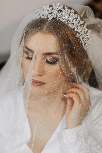 Premium Photo Wedding Portrait Blonde Bride In A Silk Suit And Tiara Poses Behind A Sheer Veil
