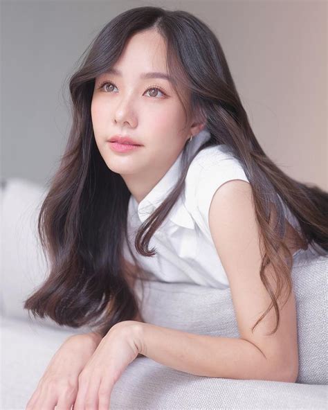 A Woman Sitting On Top Of A Couch Next To A White Wall With Long Hair