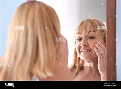 Mature Woman Looking In Mirror At Home Stock Photo Alamy