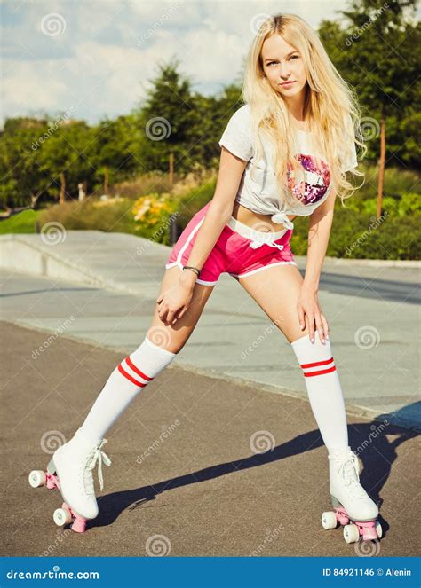 Beautiful Blonde Girl Posing On A Vintage Roller Skates In Pink Shorts And White T Shirt On A