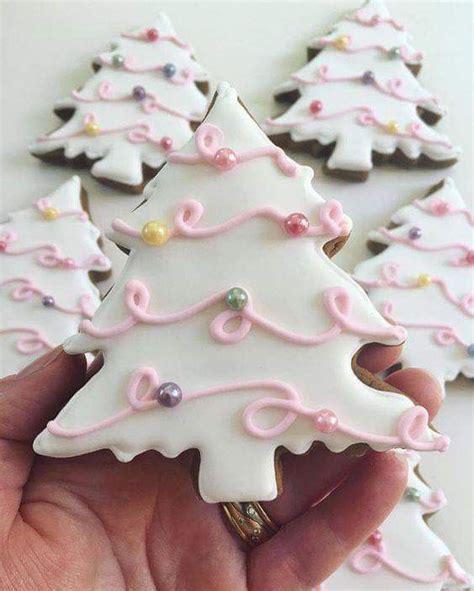 A Hand Holding Some Decorated Cookies In The Shape Of Christmas Trees